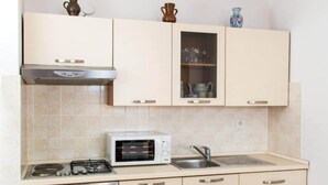 A kitchen with a stove, microwave, oven, and a sink.