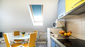 A modern kitchen with a dining area, a skylight, and a fruit bowl on the counter. - Apartments & Rooms Sunshine Home - Studio Apartment (Vela Luka)