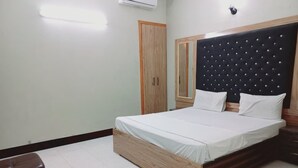 A bedroom with a bed, a wardrobe, and a nightstand. - Cosy inn Near Millennium Mall  (Karachi)