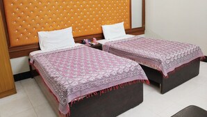 A double bed with a patterned bedspread and a wooden headboard with a tufted design. - Cosy inn Near Millennium Mall  (Karachi)