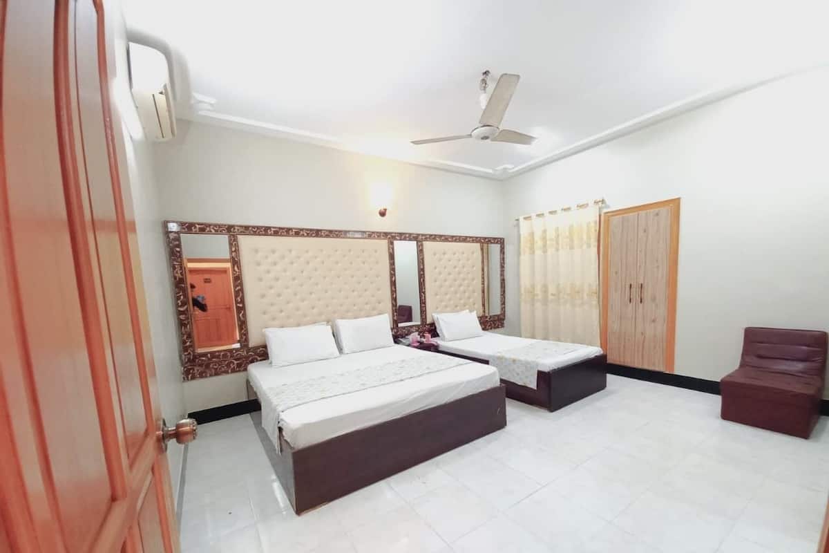 A bedroom with two beds, a wardrobe, a mirror, and a ceiling fan.