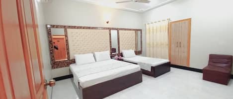 A bedroom with two beds, a wardrobe, a mirror, and a ceiling fan.