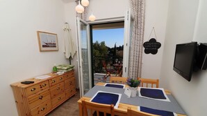 Ein Essbereich mit einem Tisch für vier Personen, einem Holzschrank und einem an der Wand montierten Fernseher.