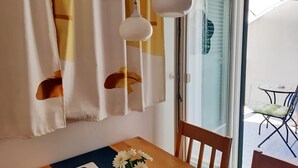 Una habitación con una mesa de madera, una silla y una ventana con cortinas.