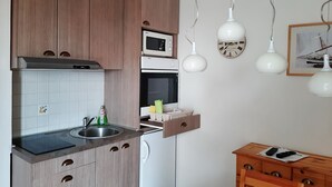 Una cocina moderna con armarios de madera, microondas, horno, lavabo y un mueble de madera con cajón.