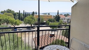 Un balcón con vista a un patio, una mesa y una sombrilla.