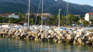 A marina with boats, a rocky breakwater, and houses in the background.