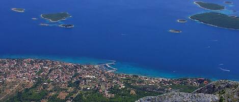 An aerial view of a coastal town with a rocky coastline, numerous small islands, and a densely built urban area with visible streets and buildings.