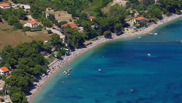 An aerial view of a coastal area with a beach, boats, and buildings.
