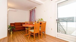 Un área de comedor con una mesa y sillas de madera, un sofá y una planta en maceta.