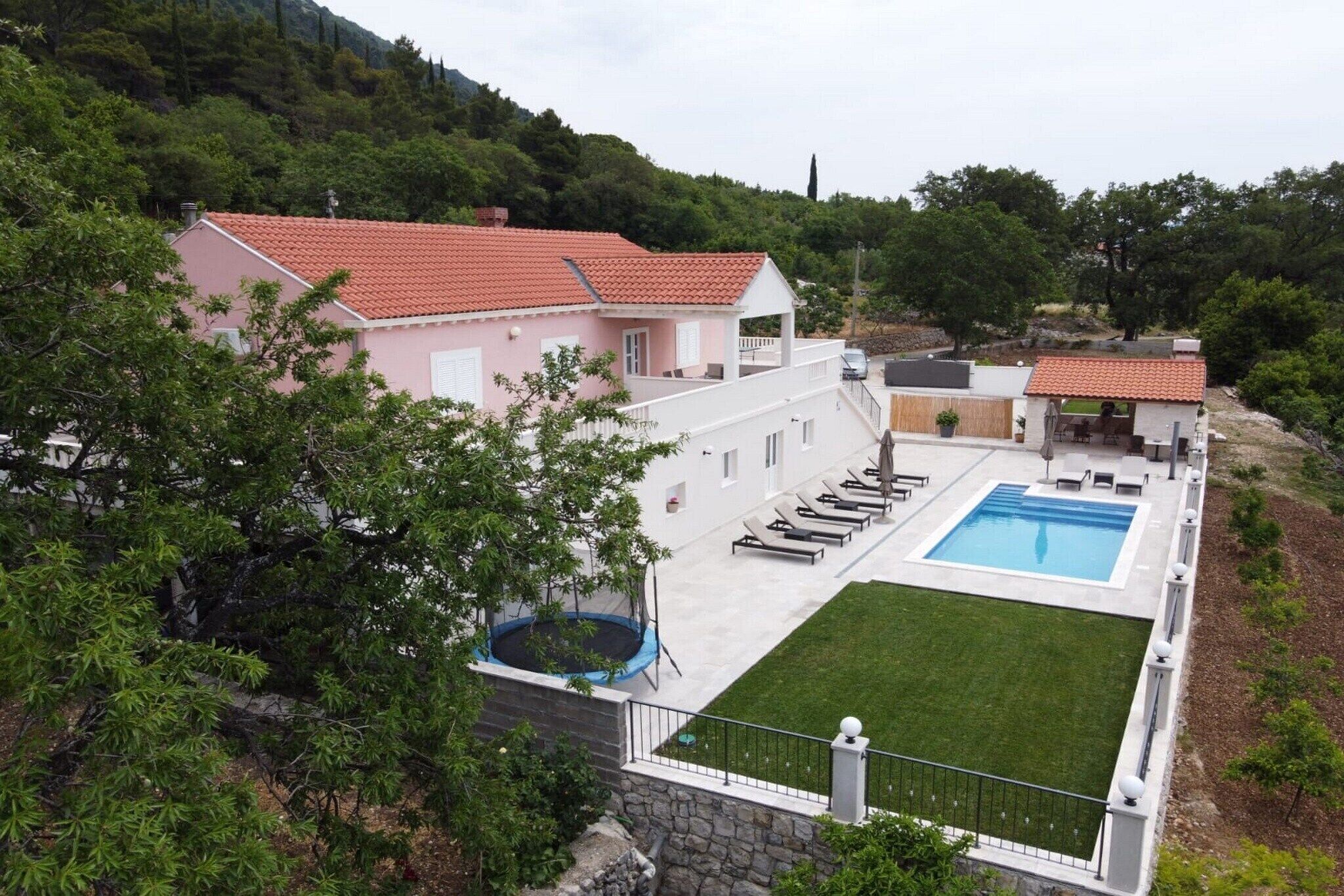 A residential property with a swimming pool, a trampoline, and a well-maintained lawn.