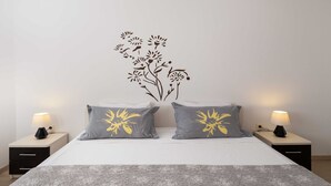 A bedroom with a bed, two nightstands, two lamps, and a wall decal of flowers.