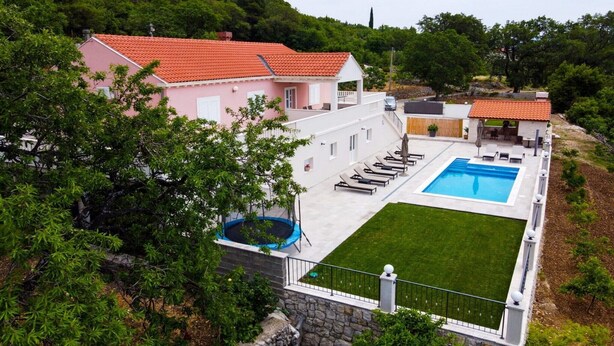 A residential property with a swimming pool, a trampoline, and a patio area with lounge chairs.
