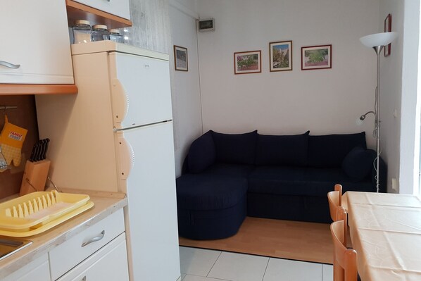 A compact living space with a kitchenette, a dark blue sofa, and a dining area. - Apartment Tereza - Two Bedroom Apartment with Terrace (Sutivan)