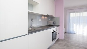 Eine moderne Küche mit weißen Schränken, einer Edelstahl-Spüle, einer Mikrowelle und einem Backofen.