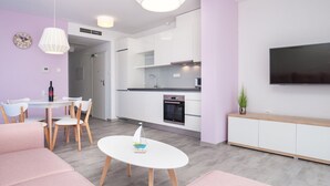 Ein modernes Wohnzimmer mit Essbereich, Küche und Fernseher.