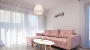Ein modernes Wohnzimmer mit einem rosafarbenen Sofa, einem weißen Couchtisch und transparenten Vorhängen.