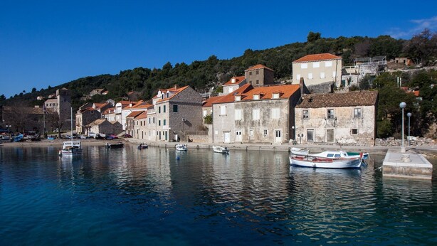 A coastal town with historic buildings along a waterfront, boats docked, and a clear blue sky. - Mali Skoj Apartment - Two-Bedroom Apartment with Sea View (Sudurad)