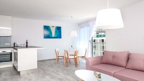 Ein modernes Wohnzimmer mit einem rosafarbenen Sofa, einem weißen Couchtisch und einem Essbereich mit Holzkreisen und einem weißen Tisch.