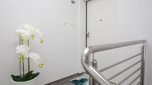Eine weiße Topforchidee auf einer Treppe mit einer Metallhandlauf.