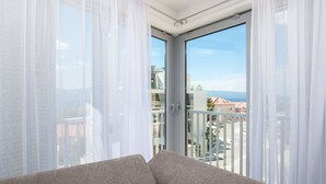 A balcony with a sofa, sheer curtains, and a clear view of buildings and mountains. - Apartments Dva Galeba - One Bedroom Apartment with Sea View (206) (Bol)