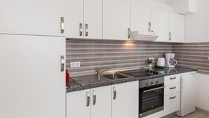 A modern kitchen with white cabinets, a stainless steel sink, a built-in oven, and a coffee maker. - Villa Celenca - Two Bedroom Apartment with Terrace and Pool View - A1 (Mokosica)