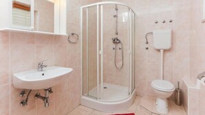 Ein modernes Badezimmer mit einer einteiligen Duschkabine, einem Waschbecken und einer Toilette.