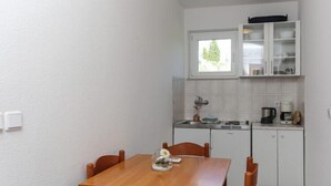Eine kleine Küche mit weißen Schränken, einem Fenster über der Spüle und einem Esstisch mit Stühlen.