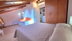 Ein Schlafzimmer mit Bett, Holzbalkendecke, Kleiderschrank und Nachttisch.