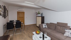 Ein modernes Wohnzimmer mit einem braunen Sofa, einem Esstisch mit Stühlen und einer kleinen Küchenzeile.
