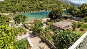 Un balcón con vista a una bahía turquesa, rodeado de exuberante vegetación y un paisaje montañoso.