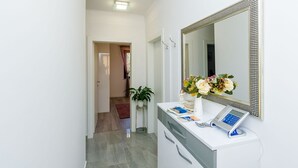 A modern bathroom with a white vanity, a large mirror, and a small potted plant.