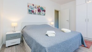 A bedroom with a bed, nightstands, a wardrobe, and a floral painting on the wall.