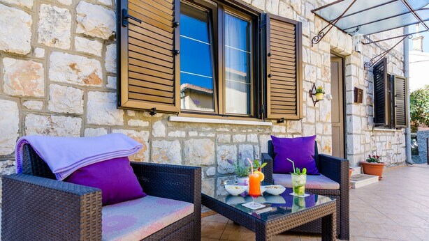 A stone building with wicker furniture and a glass table.