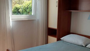Un dormitorio con cama, ventana con cortinas y armario de madera.