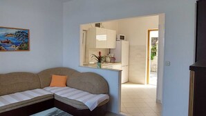 Una sala de estar con un sofá, una mesa de centro, un cuadro y vista a la cocina.