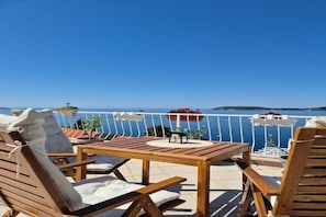 A wooden table and chairs on a balcony with a view of the sea. - Apartments Matea - One-Bedroom Apartment with Sea View - (Štikovica) (Stikovica)