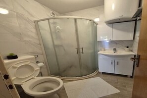 A bathroom with a glass-enclosed shower, a toilet, and a sink with cabinets. - Apartments Matea - One-Bedroom Apartment with Sea View - (Štikovica) (Stikovica)