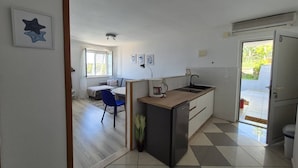 Cocina compacta con lavamanos, un refrigerador pequeño y una zona de comedor con una silla y mesa.