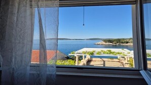 Una habitación con un amplio ventanal con vistas a una playa y al mar.