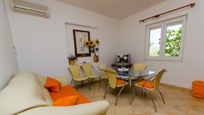 A living room with a beige sofa, yellow chairs, a glass table, and a TV. - Apartments Ivana (TR) - One Bedroom Apartment with Terrace (A3) (Trogir)