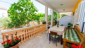 A balcony with a stone floor, a table with chairs, a bench, and potted plants. - Apartments Ivana (TR) - One Bedroom Apartment with Terrace (A3) (Trogir)