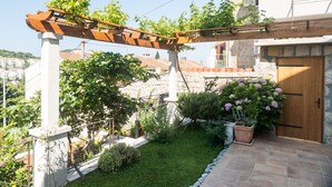 A garden with a pergola, a wooden door, and a stone wall.