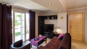 A living room with a sofa, a coffee table, a TV, and a sliding glass door.