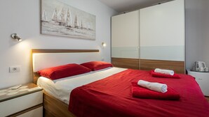 Ett hotellrum med en säng, en tavla, en garderob och ett nattduksbord med en vattenkokare.