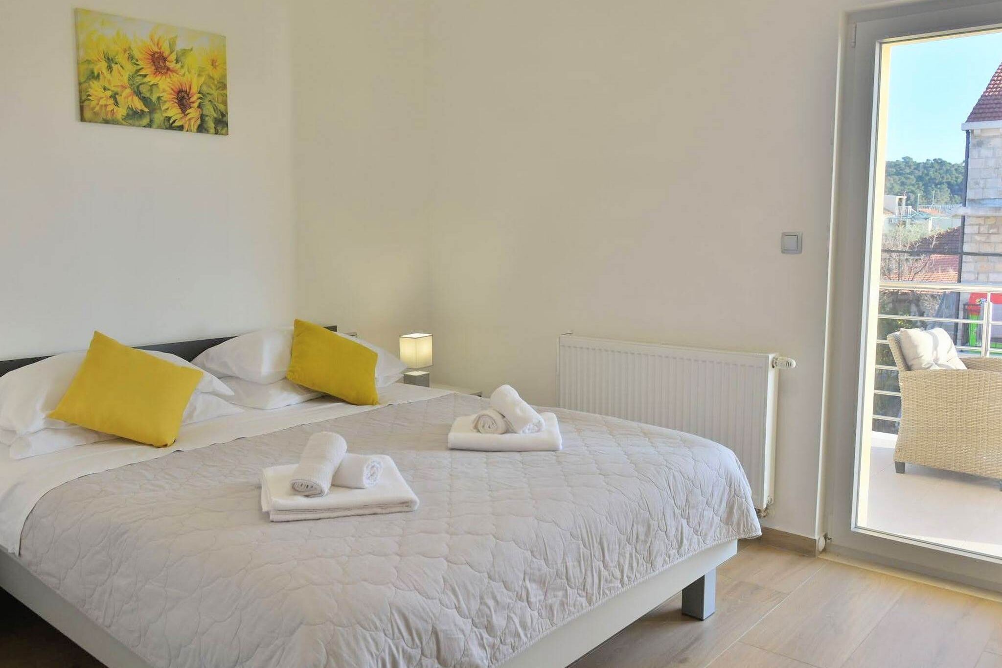 Une chambre d’hôtel avec un grand lit, deux oreillers jaunes, une couvre-lit blanche matelassée et des serviettes soigneusement pliées.