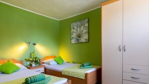 Ein Hotelzimmer mit zwei Betten, grünen Wänden, einem großen Kleiderschrank und einem Blumenbild.