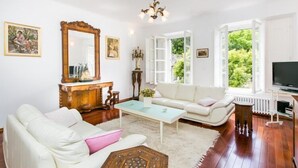 A living room with a white sofa, a coffee table, a wooden cabinet, a large mirror, and a television.