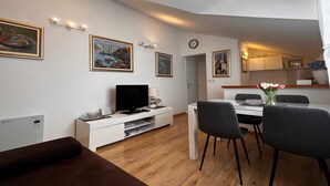 Un soggiorno moderno con televisione a schermo piatto, tavolo da pranzo, sedie e opere d'arte alle pareti.