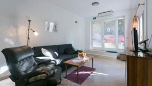 A modern living room with a leather sofa, a wooden coffee table, and a glass door leading outside. - Apartment Anita (Gruž) - One-Bedroom Apartment with Balcony (Dubrovnik)